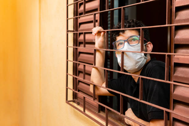 Man looking out the window during social isolation.