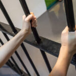 Hands holding metal black bar with stress. Imprison concept.
